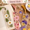 Marque-page fleuri fait main avec des fleurs pressées sur un fond de livre ouvert